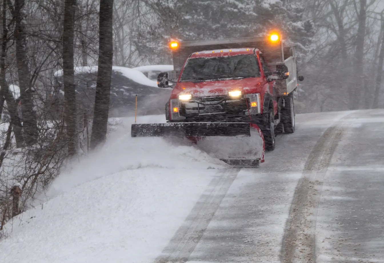 red commercial snow removal truck clearing snow from the road